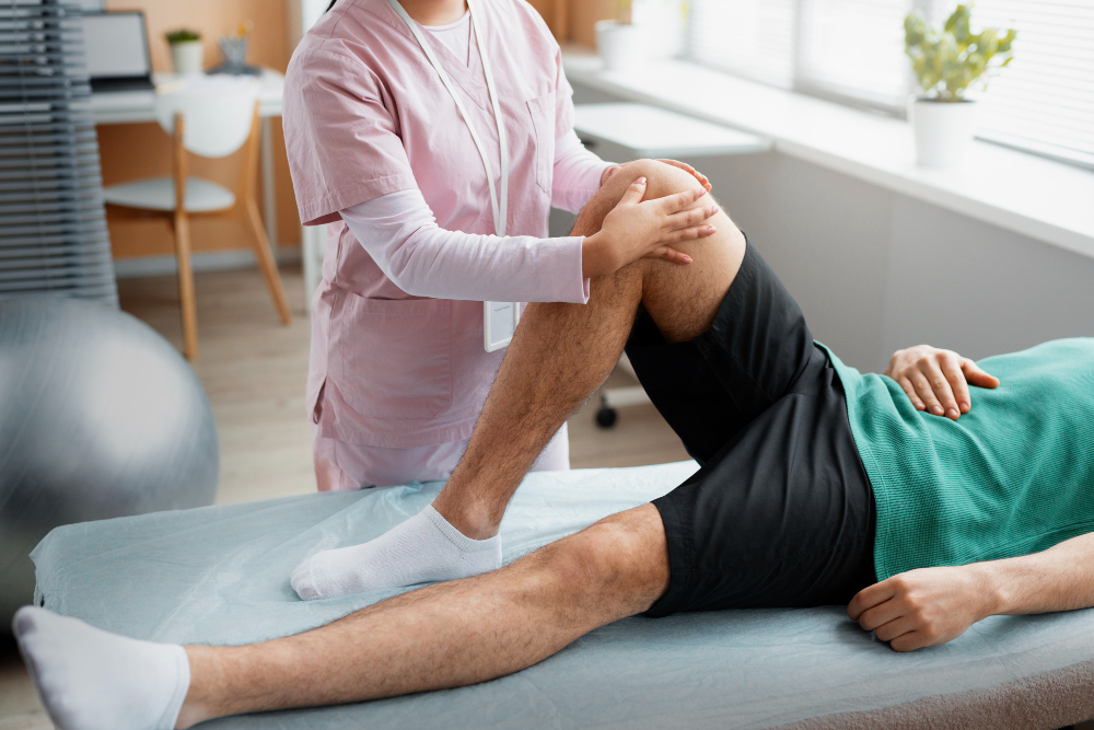 Doctor assisting a patient with knee pain during a rehabilitation session, supporting their leg and guiding a physio exercise in a clinical setting.