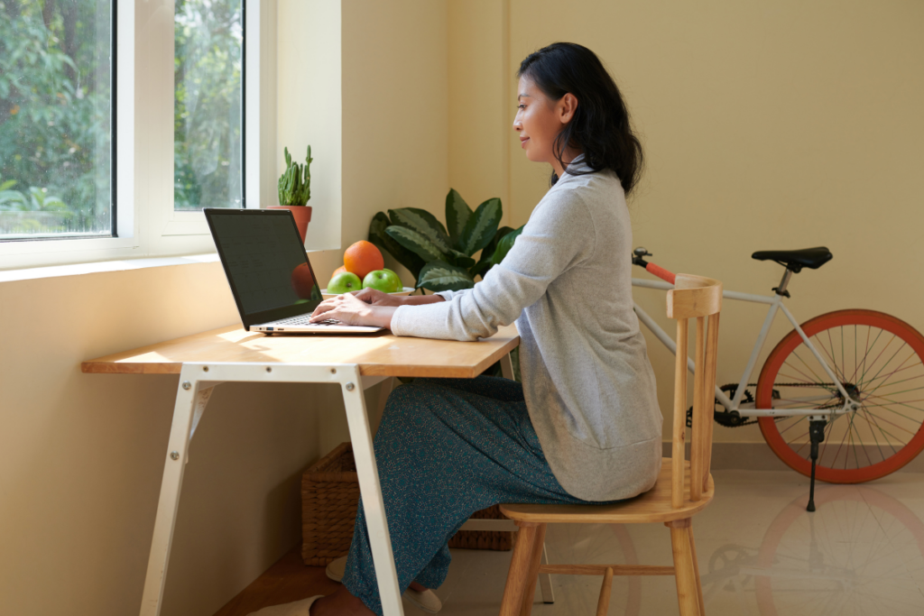 Woman sitting upright at desk with laptop, demonstrating healthier desk setup compared to poor posture habits